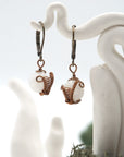 Front angle of rainbow moonstone drop earrings hanging on a jewelry display, wire-wrapped design.