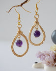 Closeup of gold plated copper wire wrapped amethyst teardrop earrings showing 8mm polished February birthstone bead and details