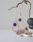 Closeup of silver plated copper wire wrapped amethyst teardrop earrings showing 8mm polished February birthstone bead and details