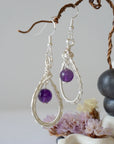 Side view of wire wrapped amethyst dangle earrings in silver plated copper with fish hook ear wires and teardrop frame