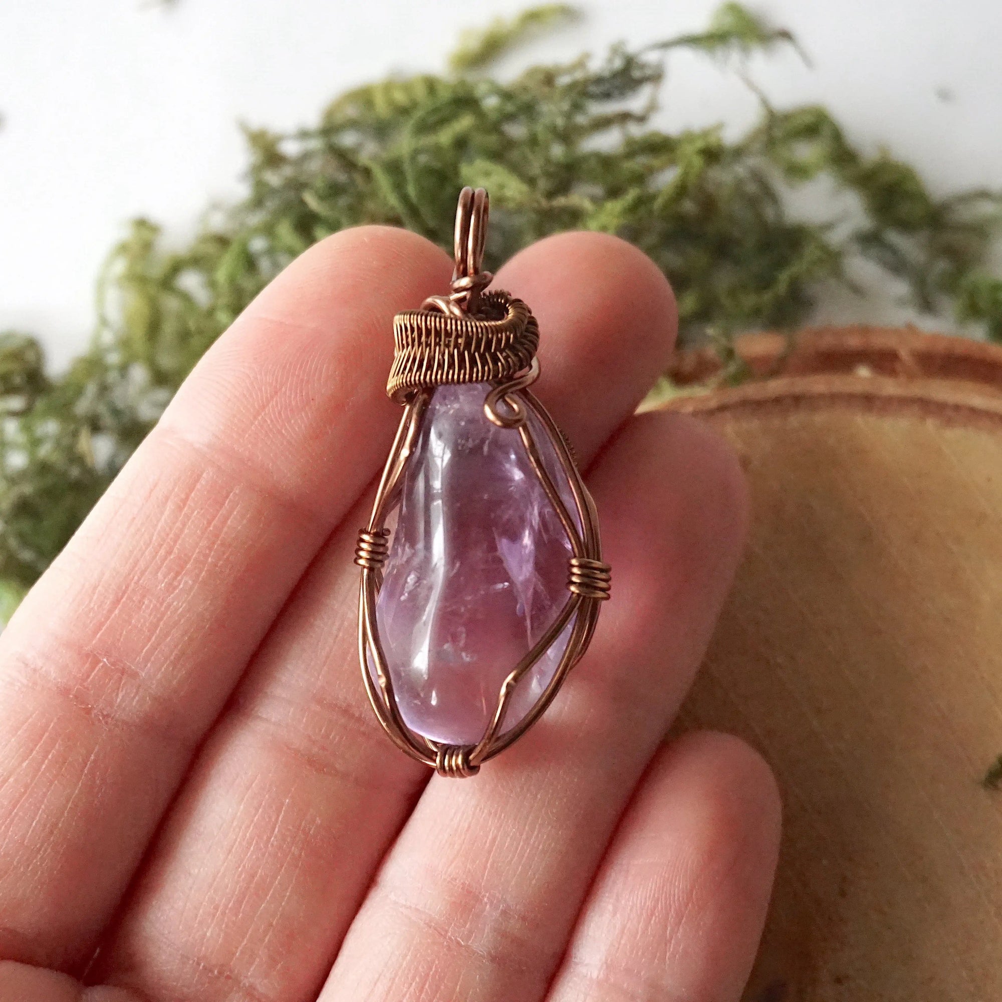 Women’s amethyst necklace in hand for size reference, lighter violet amethyst, antique bronze copper wire wrap