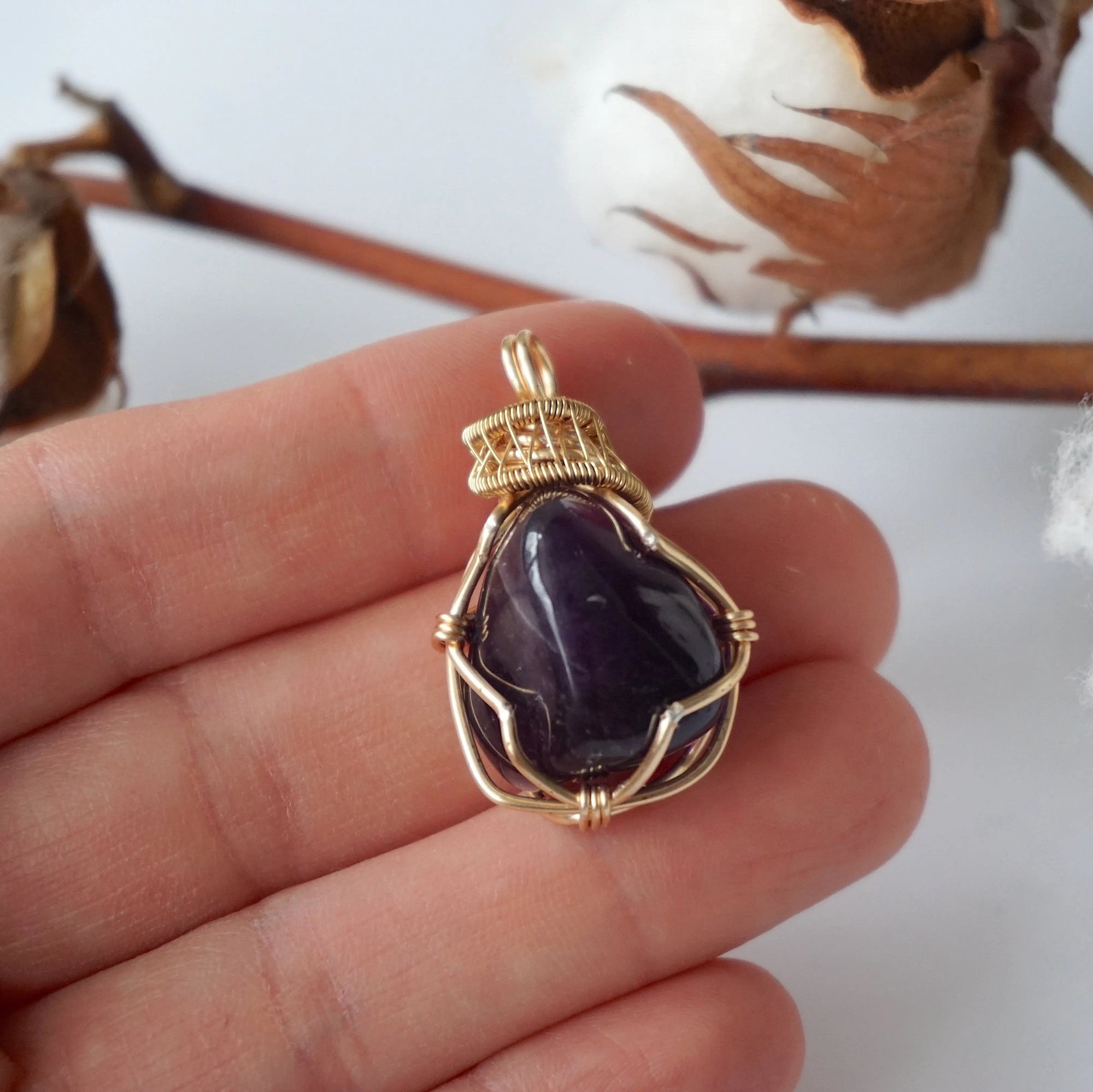 Women’s gold amethyst necklace shown in hand for size reference, polished dark amethyst pendant, artisan gold plated copper wire wrap