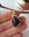 Women’s gold amethyst necklace shown in hand for size reference, polished dark amethyst pendant, artisan gold plated copper wire wrap
