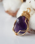 Left side angle of women’s gold amethyst necklace, polished dark amethyst pendant, artisan gold plated copper wire wrap