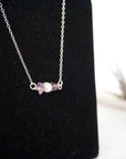 Focused left-side close-up of sterling silver amethyst and pearl bar necklace on jewelry display