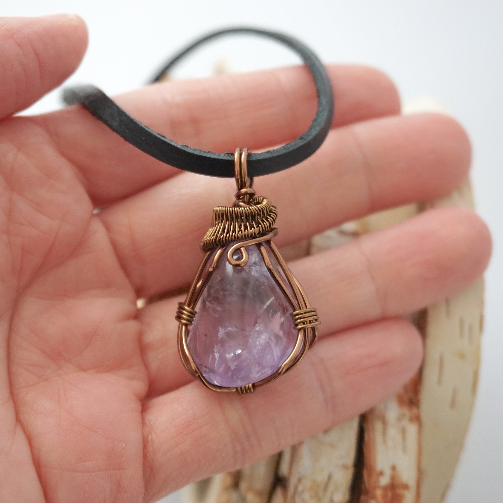 Handmade amethyst mens pendant held in hand showing size — natural polished-raw amethyst stone wire wrapped in bronze copper finish, 40-60 carats, one of a kind