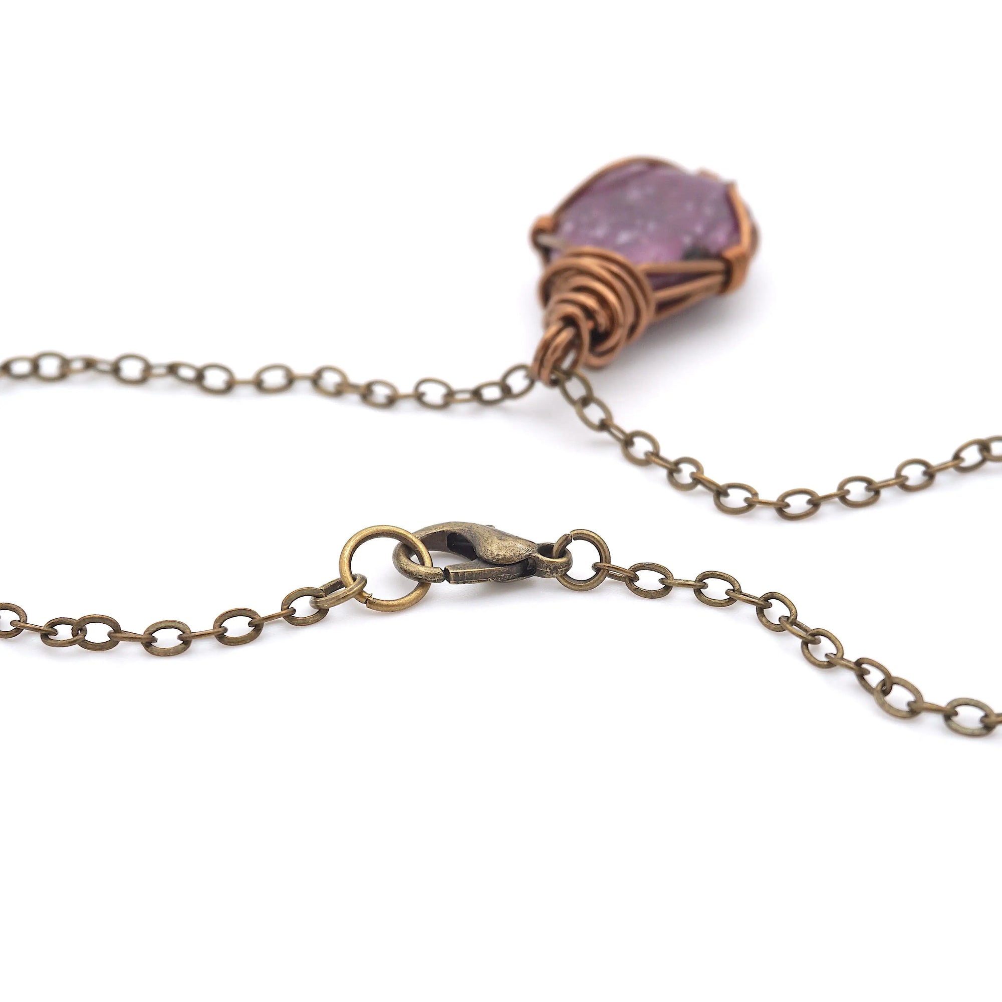 Close-up of antique bronze lobster clasp and cable chain on handmade raw ruby necklace — nickel-free jewelry detail