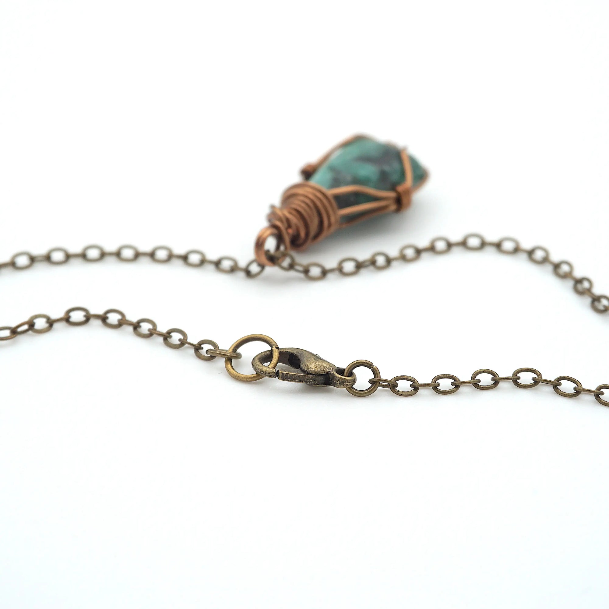 Detail of antique bronze cable chain and lobster clasp closure for handcrafted emerald necklace.