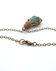 Detail of antique bronze cable chain and lobster clasp closure for handcrafted emerald necklace.