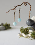 Aquamarine drop earrings on display, angled view, simple artisan design, antique bronze finish