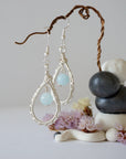 Zoomed out look at aquamarine earrings, artisan wire wrapped, soft silver finish, March birthstone