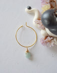 Flat lay of a gold plated aquamarine hoop drop earring, highlighting the wire wrapped natural aquamarine gemstone and minimalist hoop design