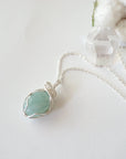 Aquamarine pendant necklace for women on a silver chain laying flat, artisan wire wrapped, soft silver over copper, Designs by Nature Gems