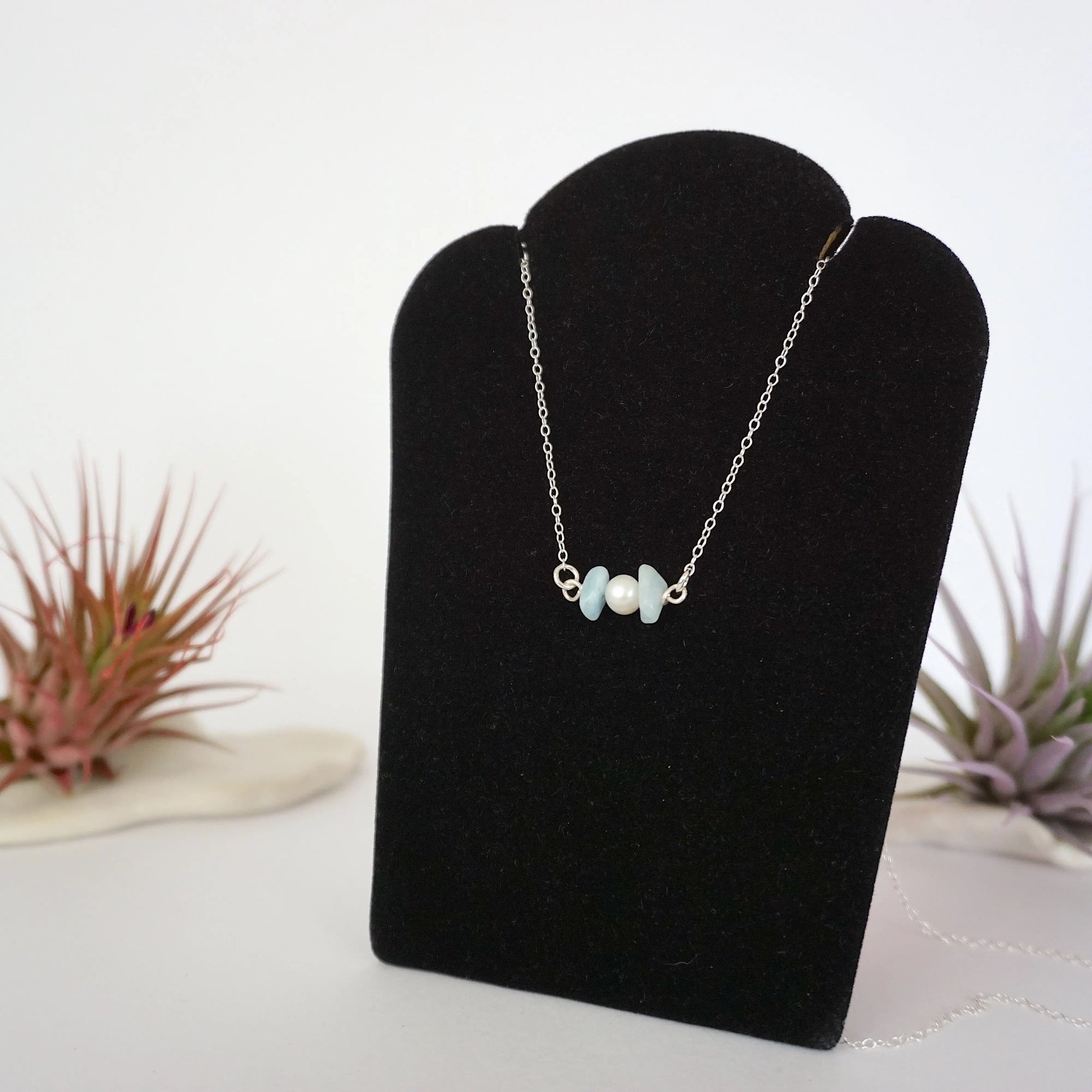 Left angle view of aquamarine and pearl bar necklace in 925 sterling silver on jewelry display