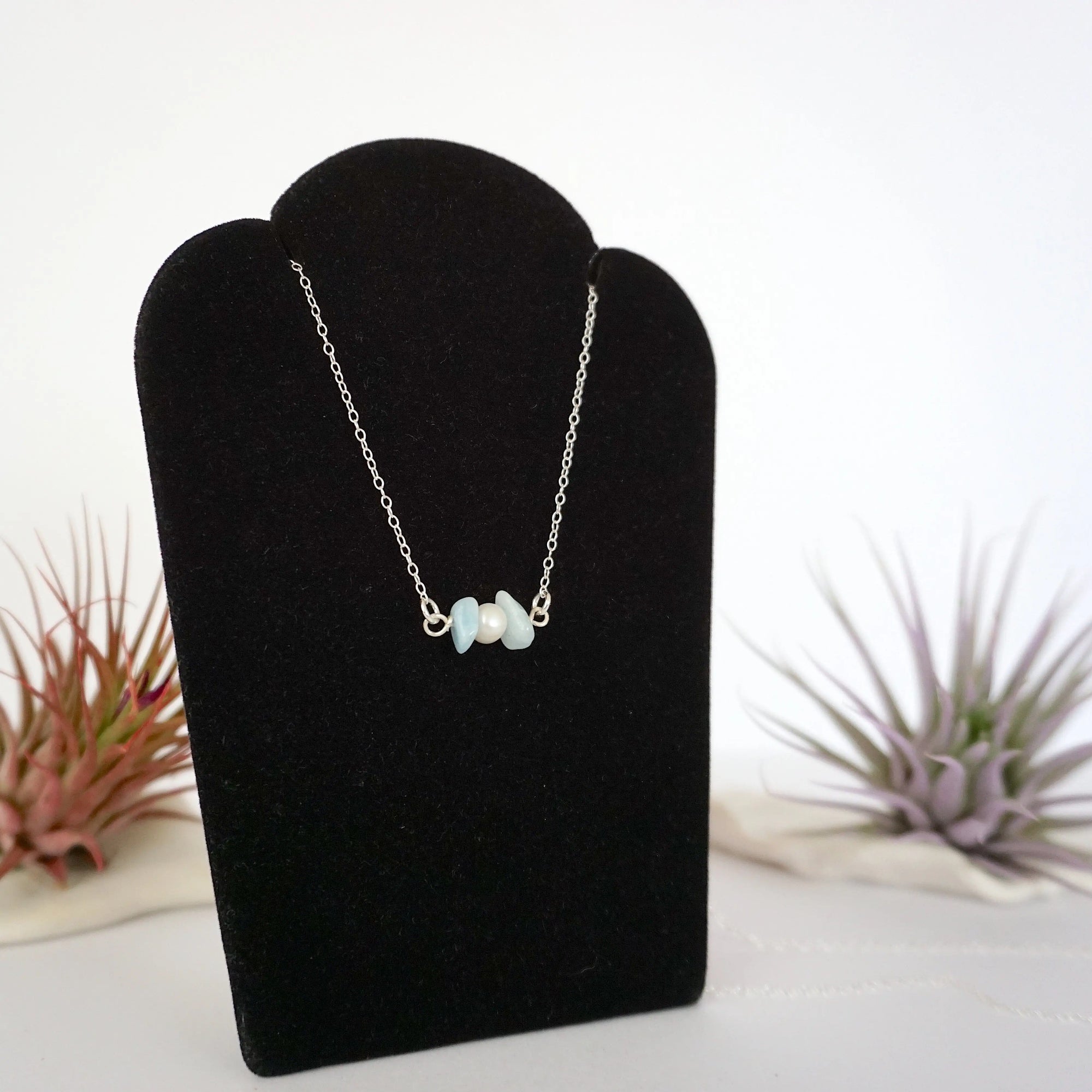 Right angle view of aquamarine and freshwater pearl bar necklace in 925 sterling silver on jewelry display