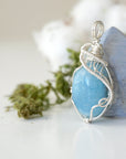 Left side view of aquamarine pendant showing intricate artisan wire wrapping and natural crystal shape