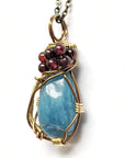 Front view of an aquamarine pendant necklace with garnet accents on an antique bronze chain