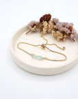Handmade aquamarine bracelet displayed on ceramic tray showing natural blue crystals and gold chain - March birthstone gift for her