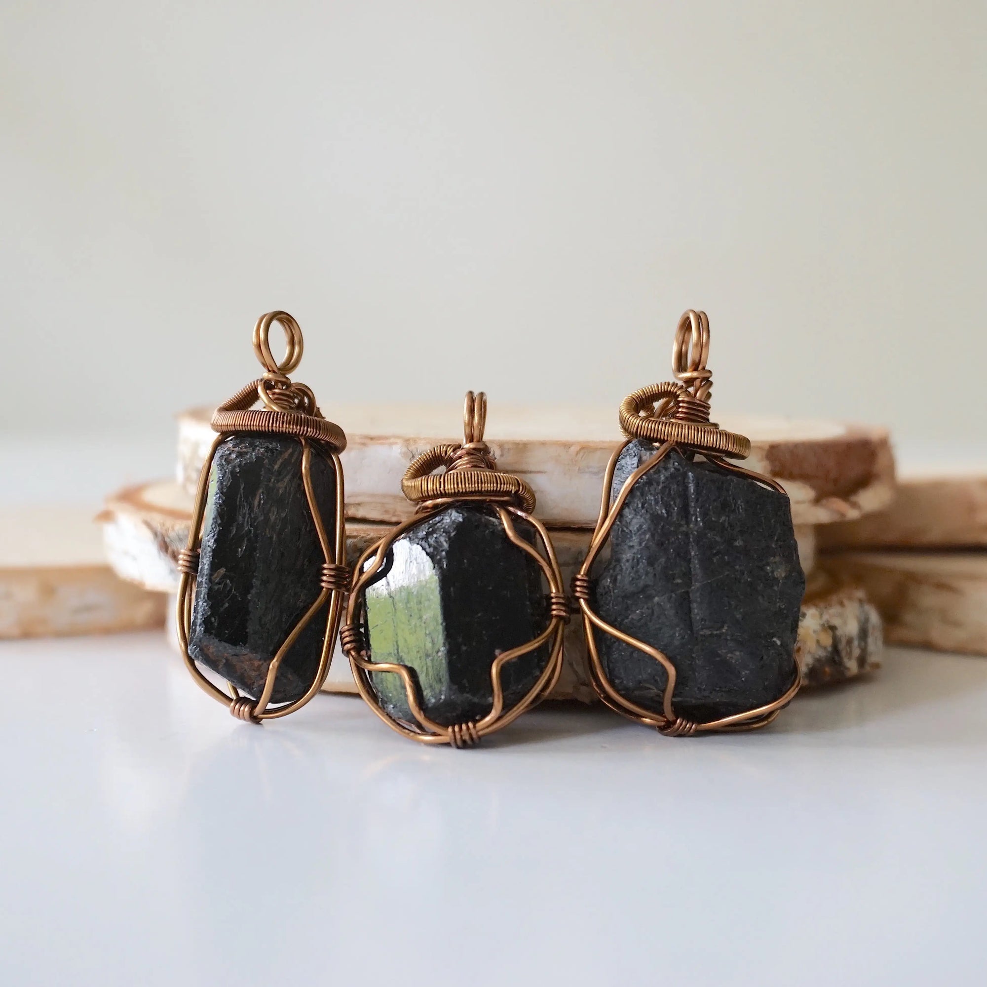 Three raw black tourmaline pendants showing natural stone variation in size and shape, artisan jewelry by Designs by Nature Gems.