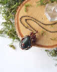 Bloodstone pendant necklace with garnet accents on an antique bronze chain, shown laying flat
