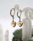Side angle of citrine drop earrings on a display stand, highlighting antique bronze copper wire wrapping.