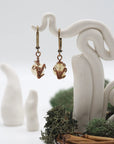 Front angle of citrine drop earrings hanging on a jewelry display, wire-wrapped design.