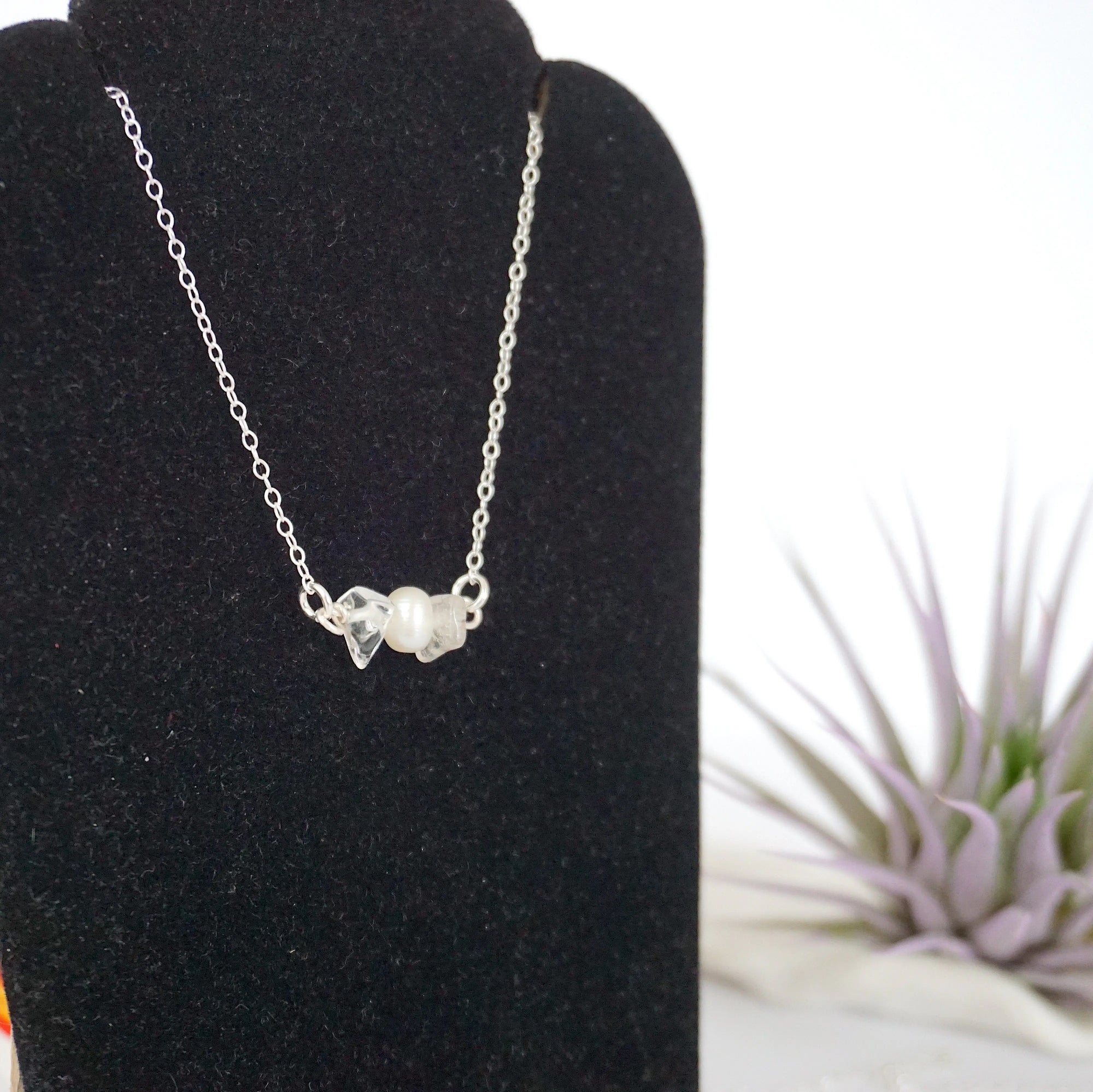 Focused left-side close-up of sterling silver clear quartz and pearl bar necklace on jewelry display
