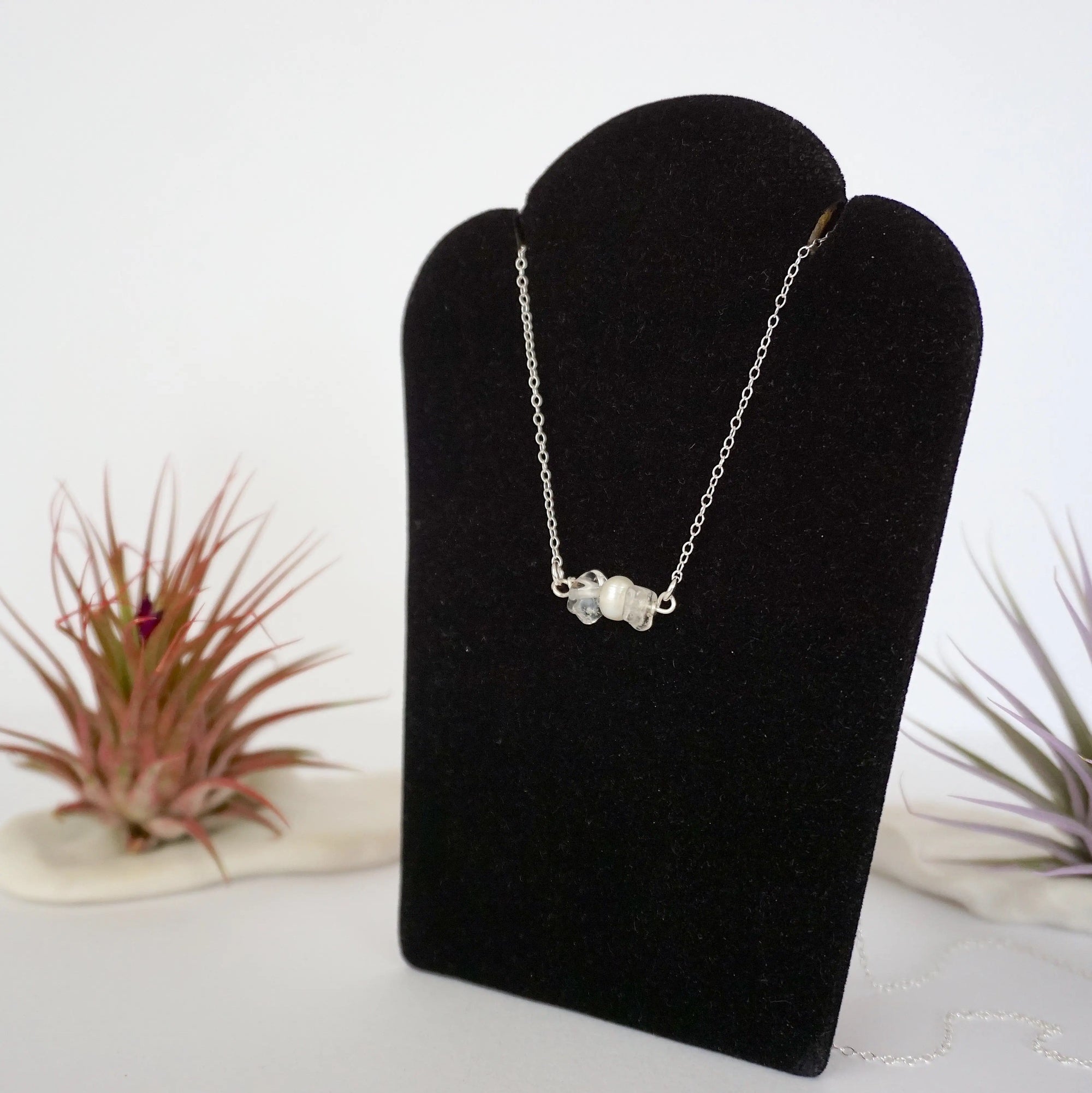 Left angle view of clear quartz and pearl bar necklace in 925 sterling silver on jewelry display