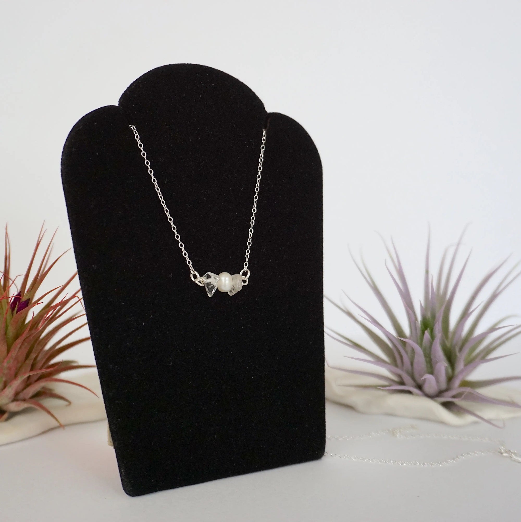 Right angle view of clear quartz and freshwater pearl bar necklace in 925 sterling silver on jewelry display
