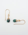Closeup showing details of emerald drop earrings, faceted emerald stone, 14k gold filled setting
