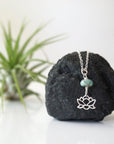 Zoomed out view of emerald and lotus necklace for women with sterling silver lotus charm on fine chain