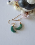 Emerald moon drop earrings in 14k gold filled displayed on a flat surface with natural faceted crescent moon emeralds.