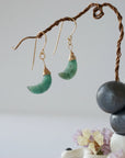 Side angle view of emerald moon drop earrings showing 14k gold filled artisan wire wrapping and faceted emerald detail.
