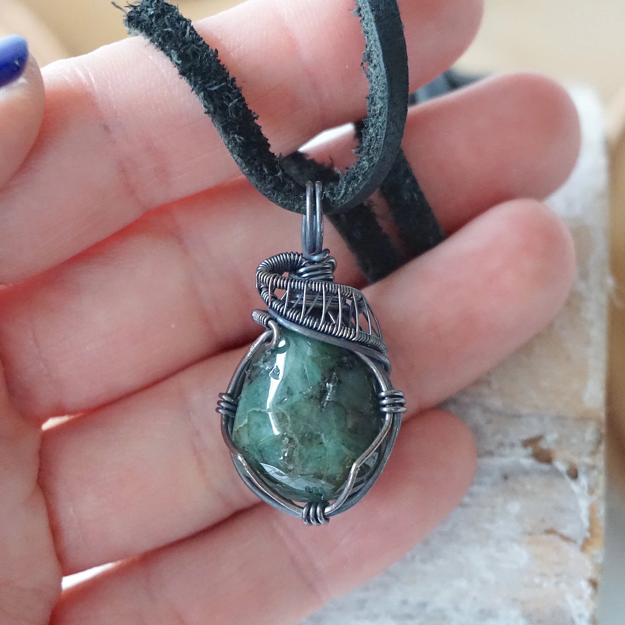 Emerald pendant necklace for men shown in hand for size reference with natural polished-raw emerald and antiqued sterling silver