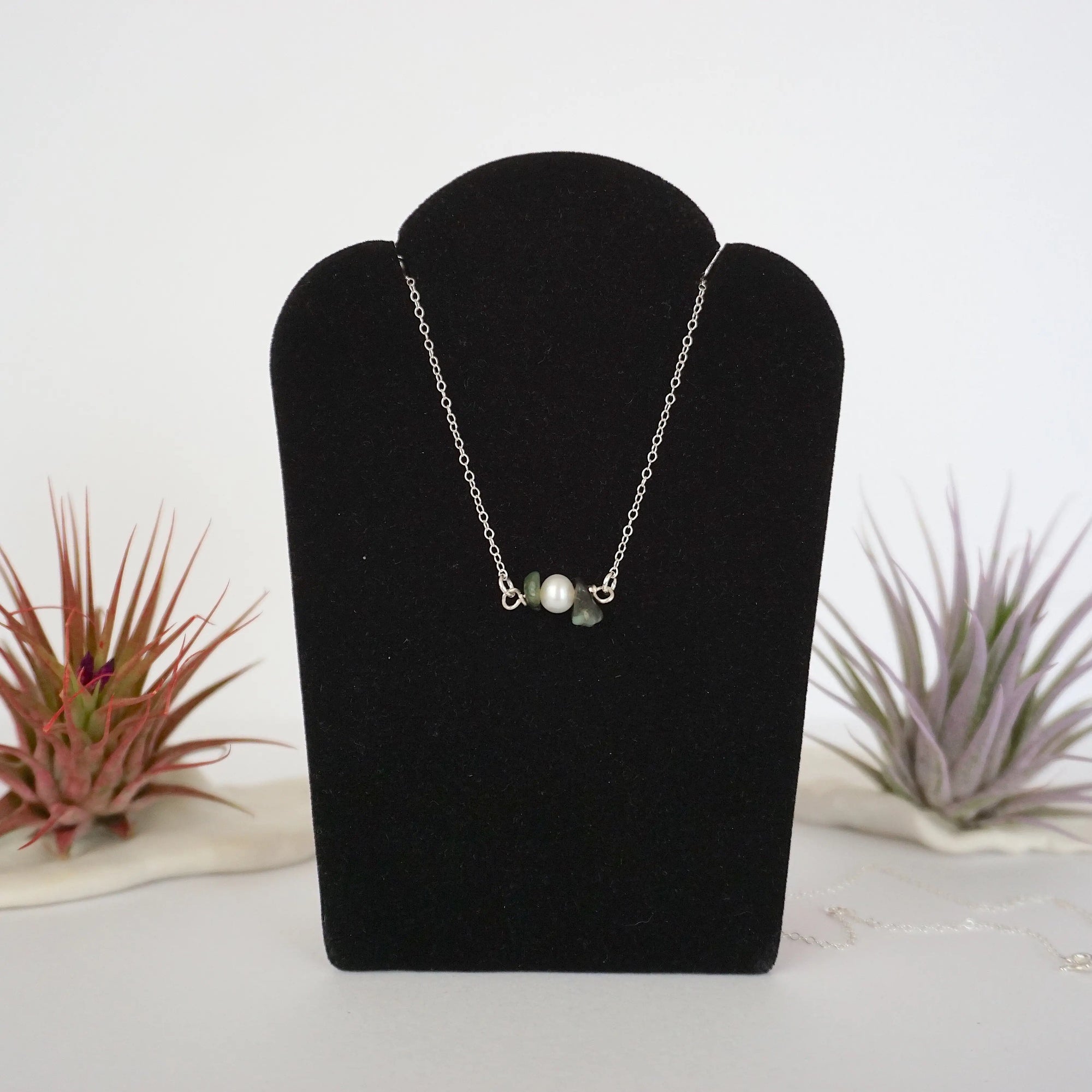 Emerald and freshwater pearl bar necklace in 925 sterling silver on jewelry display, front view