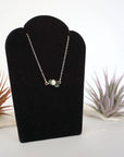 Right angle view of emerald and freshwater pearl bar necklace in 925 sterling silver on jewelry display
