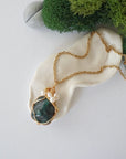 Emerald and freshwater pearl pendant on gold plated brass chain laying flat, handmade wire wrapped jewelry for women