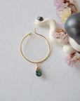 Emerald hoop drop earrings on flat surface showing faceted emerald drop and classic warm gold hoop design