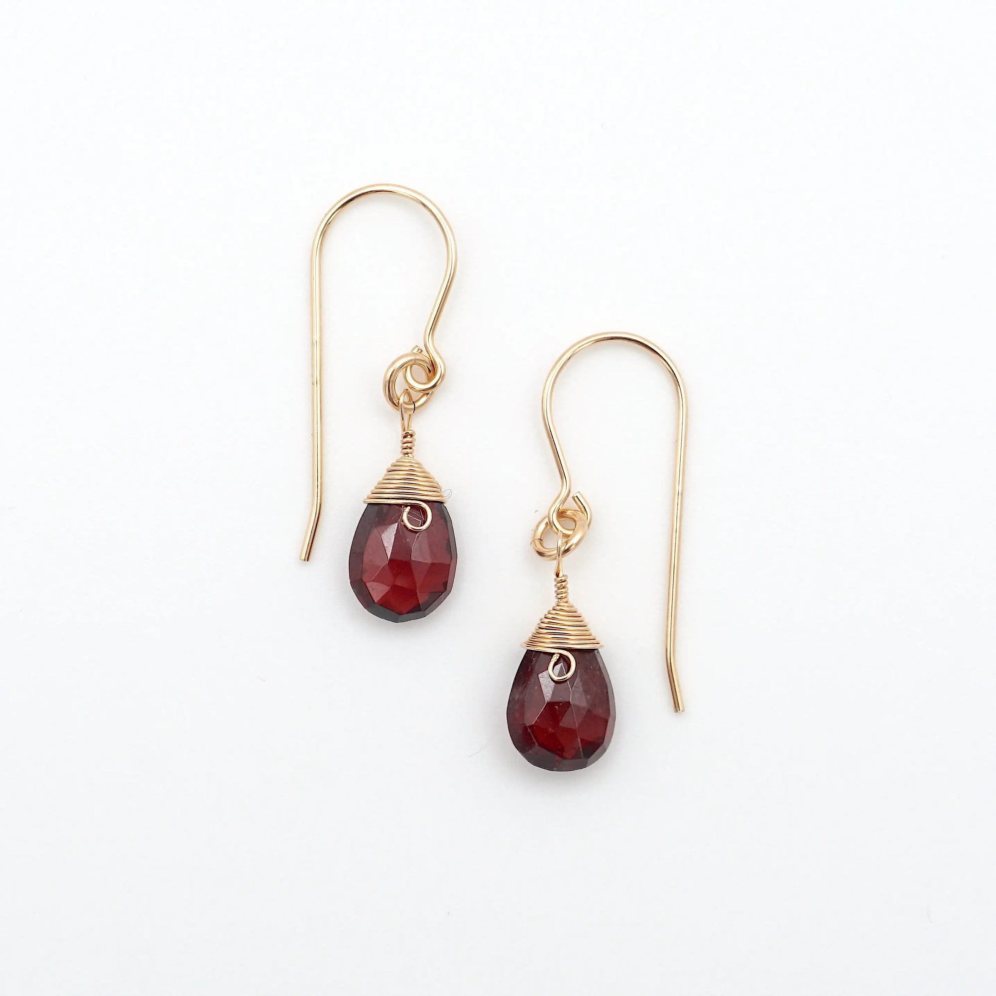 Top view flat lay of garnet 14k gold filled drop earrings showing wire wrapped faceted garnet crystals and fish hook ear wires