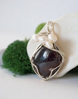 Side angle of handmade garnet and freshwater pearl pendant necklace, silver wire wrapped jewelry