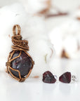 Front view of a garnet necklace and stud earrings jewelry set with an antique bronze wire wrapped pendant and sterling silver garnet studs