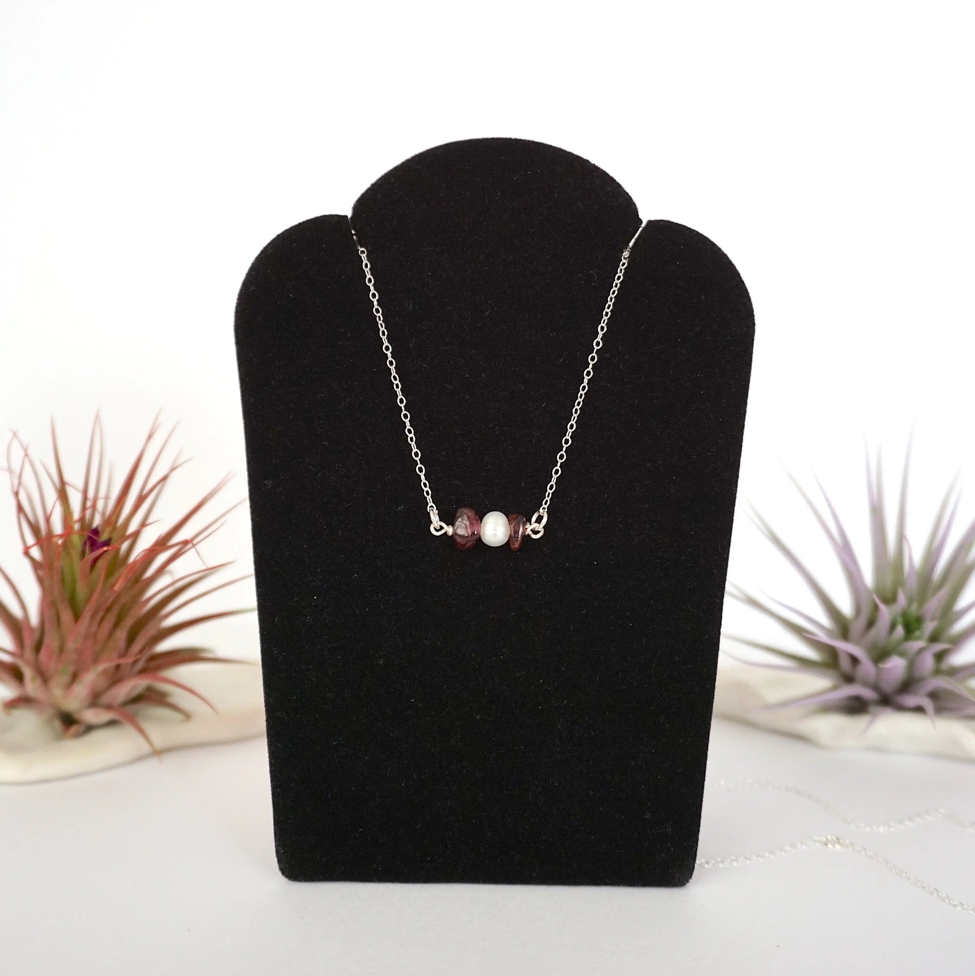 Garnet and freshwater pearl bar necklace in 925 sterling silver on jewelry display, front view