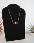 Right angle view of garnet and freshwater pearl bar necklace in 925 sterling silver on jewelry display