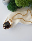 Garnet and freshwater pearl pendant on gold plated brass chain laying flat, handmade wire wrapped jewelry for women