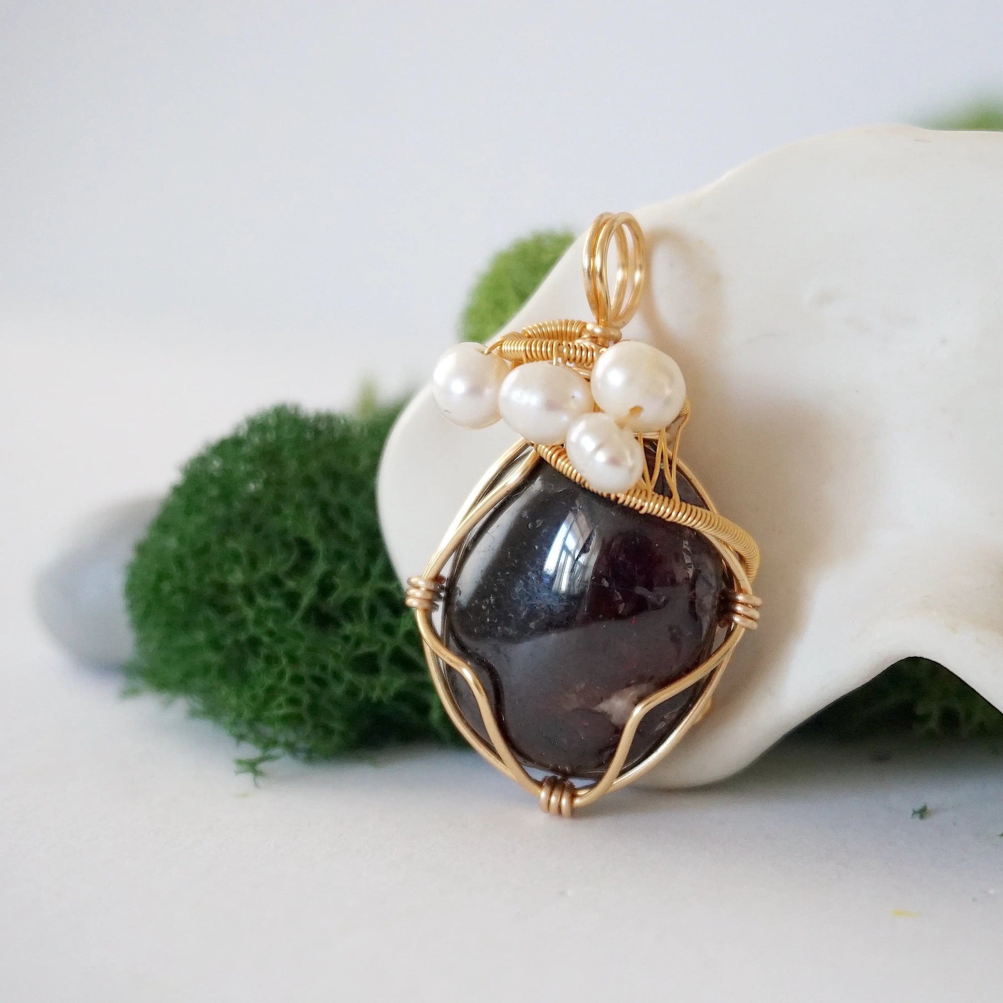 Side angle detail of garnet and freshwater pearl pendant, gold wire wrapped, ethical artisan necklace