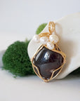 Side angle detail of garnet and freshwater pearl pendant, gold wire wrapped, ethical artisan necklace