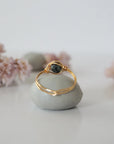 Back view of minimalist gold emerald ring highlighting handcrafted wire wrapping detail.