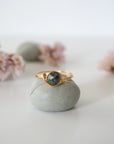 Front view of minimalist gold emerald ring with natural faceted emerald bead and artisan wire wrapping.
