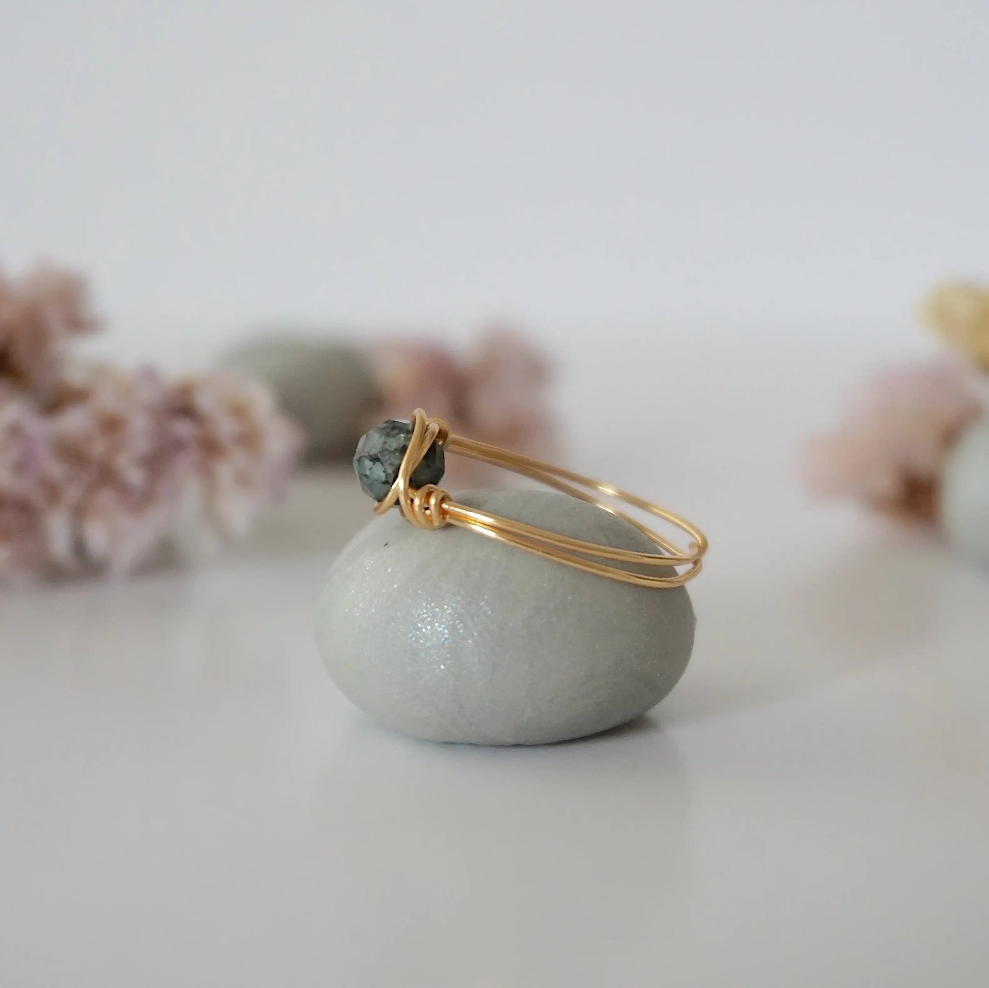 Side view of minimalist gold emerald ring showing classic artisan wire wrapping around a natural emerald bead.
