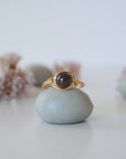 Front detail of simple garnet bead ring with minimalist gold wire wrapping on display